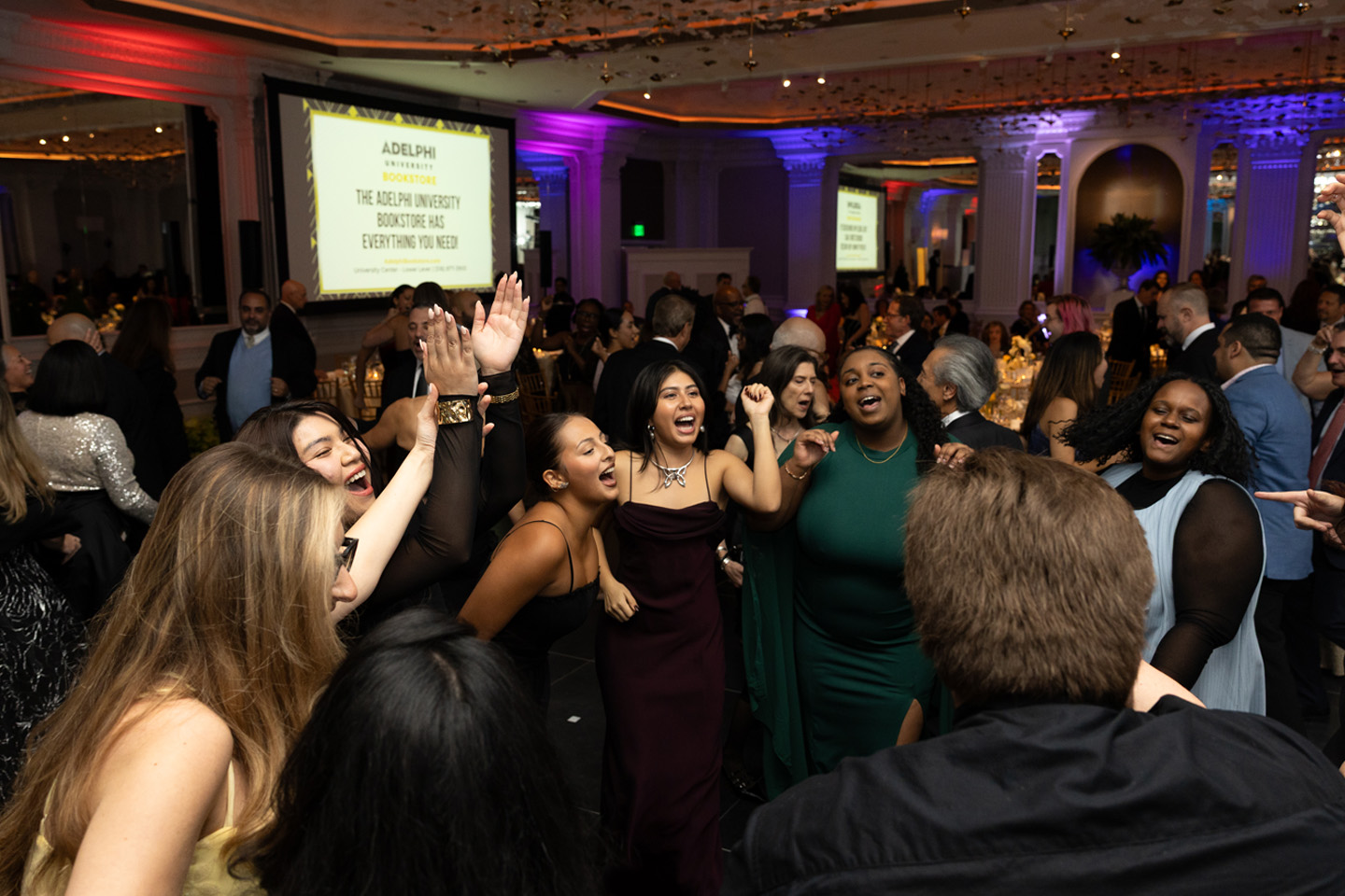 A large crowd of formally dressed attendees dance at the Gala.