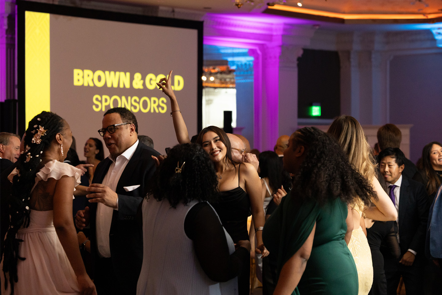 Many formally dressed attendees dance on the dance floor.