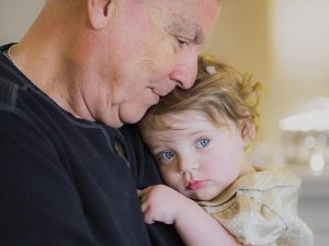 Mark W. Jordan ’63 holding and embracing his young granddaughter indoors.