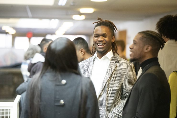 A group of students smiling and talking together at Adelphi during an event