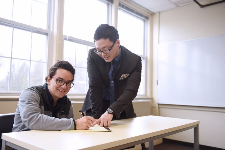 An Adelphi professor working closely with an international student in a classroom.