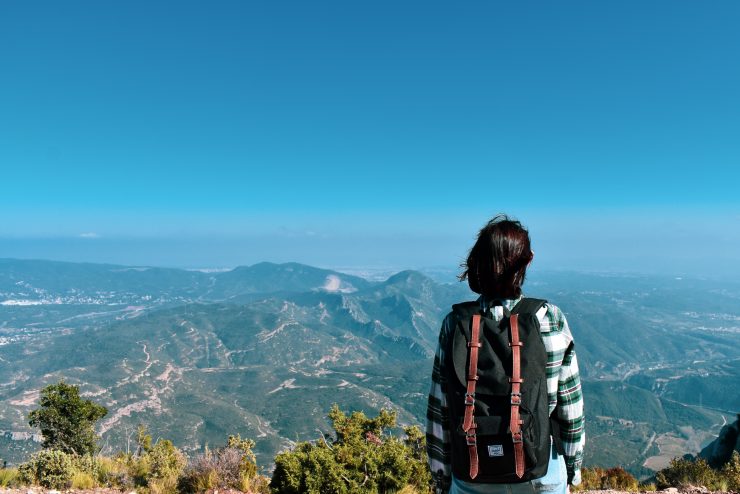 Lila Woodbridge wearing a backpack looks out onto a beautiful mountain range while studying abroad.