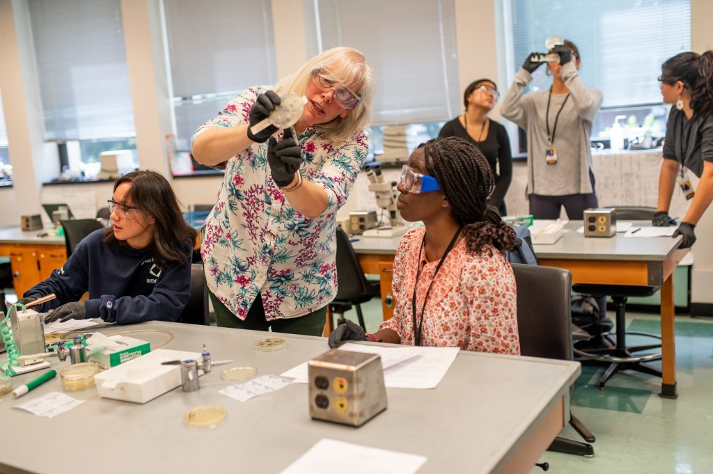 Professor Jonna M. Coombs guides pre-college students through a biology lab activity at Adelphi University’s Garden City campus.