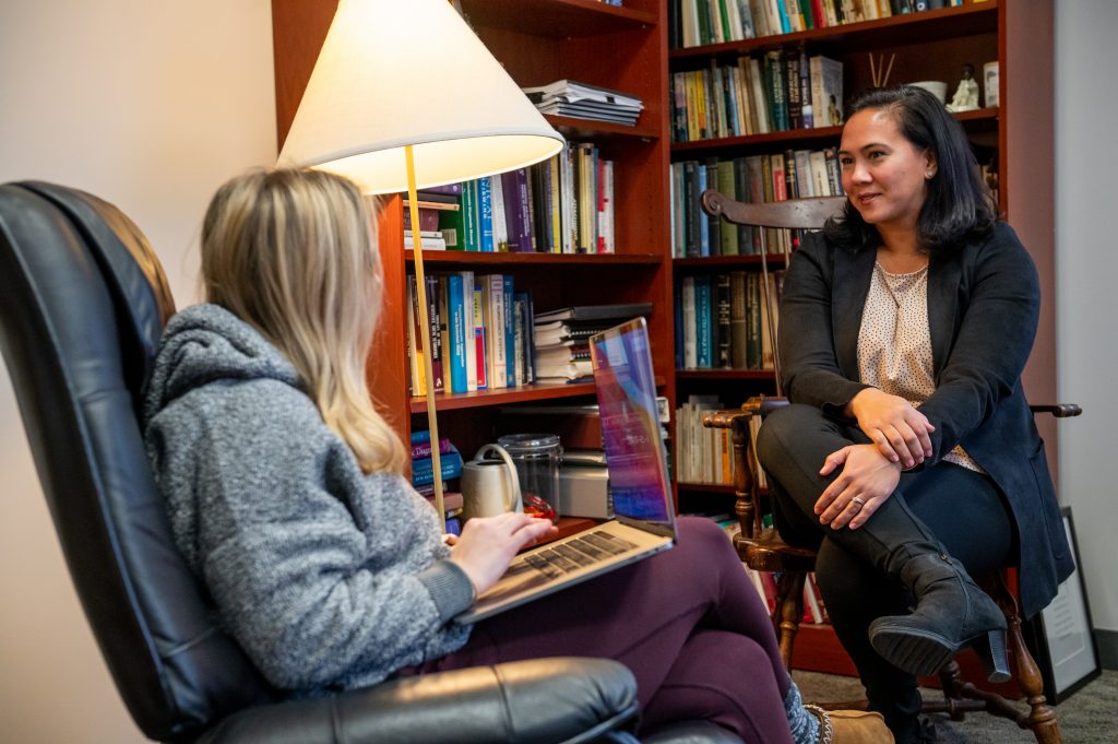 A faculty member form the Derner School of Psychology talks with a student one-on-one.