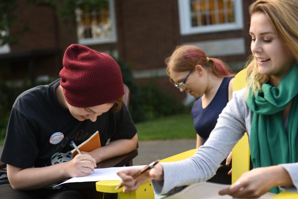 Students in Adelphi’s pre-college writing program collaborate and write together outdoors on the Garden City campus.
