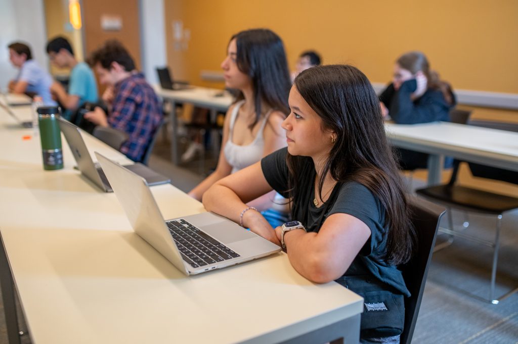 A student in Adelphi’s pre-college Communication and Critical Thinking course listens to a lecture with a laptop open in class.