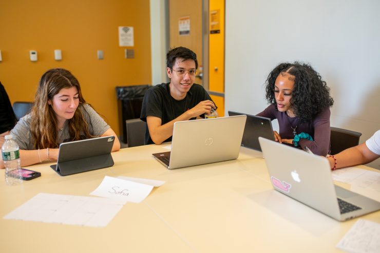 High school students work at table together with laptops at Adelphi University.