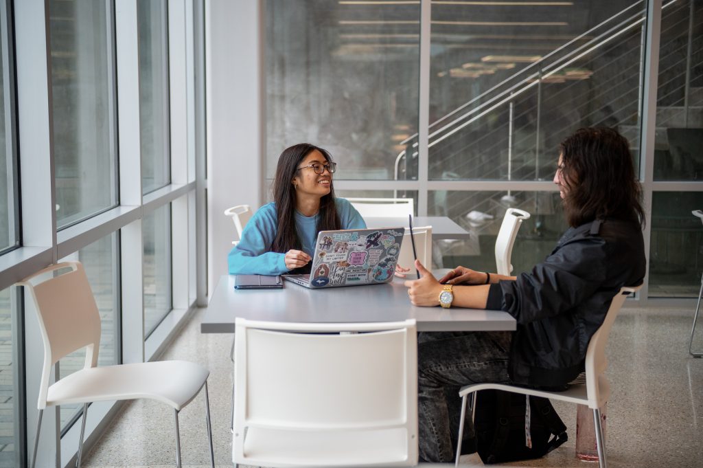 Sarah Joy Gallardo and another honors student talking at a table in the UC