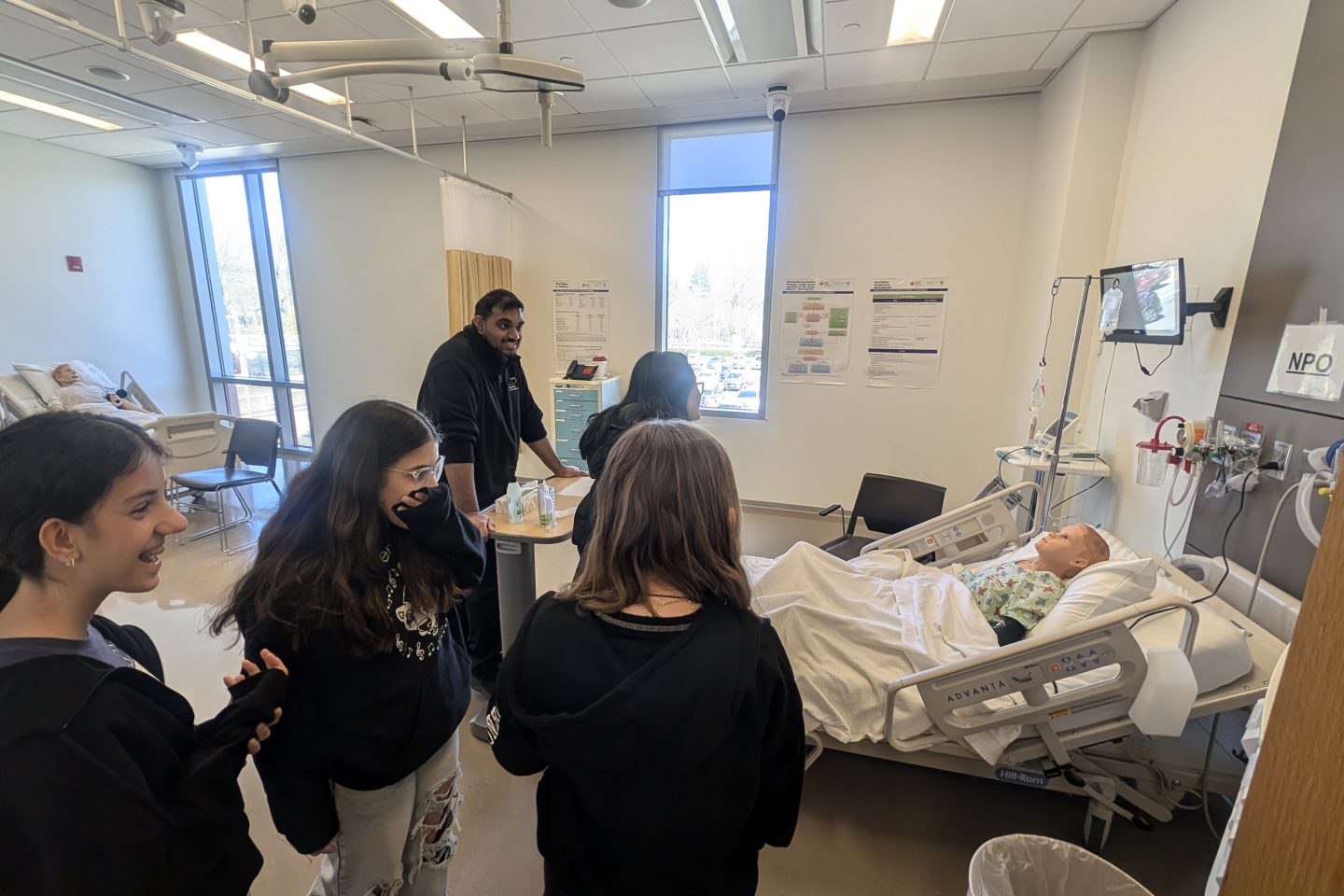Children with a student looking at a hospital bed in the sim lab