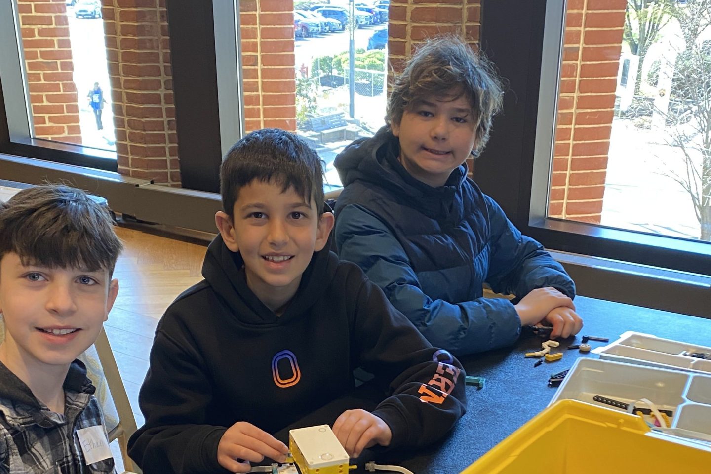 Three boys playing with legos at a table