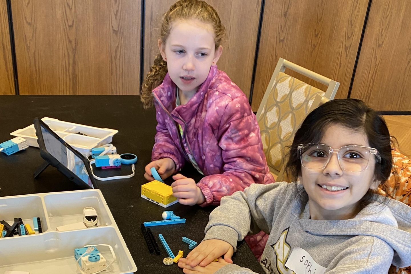 Two giels playing with legos at a table