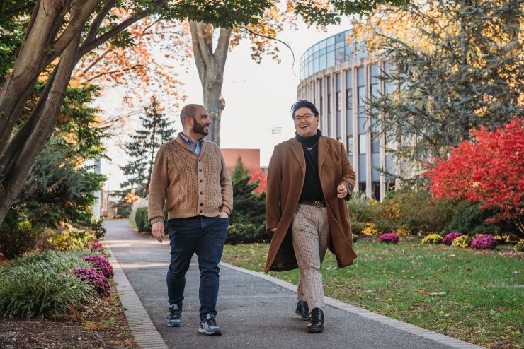 A staff member and student walk together in front of the Science Building on campus