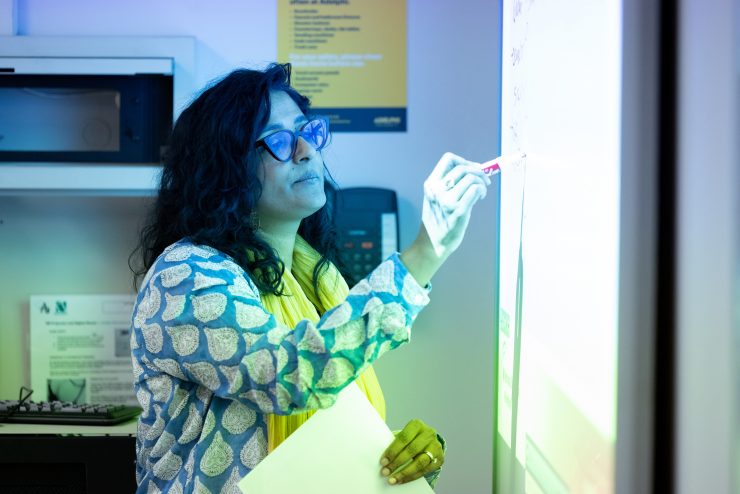 faculty member working at a whiteboard.