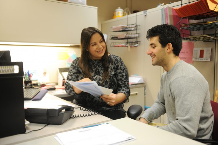 A student working at Adelphi handing someone a brochure