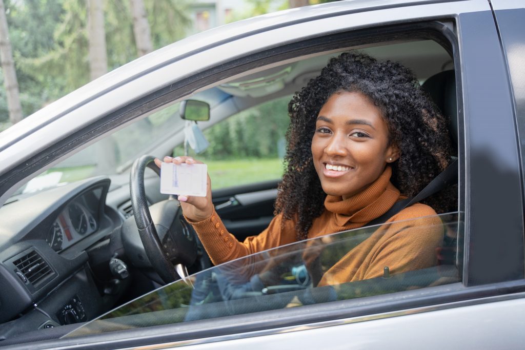 Young woman driving in a car with license