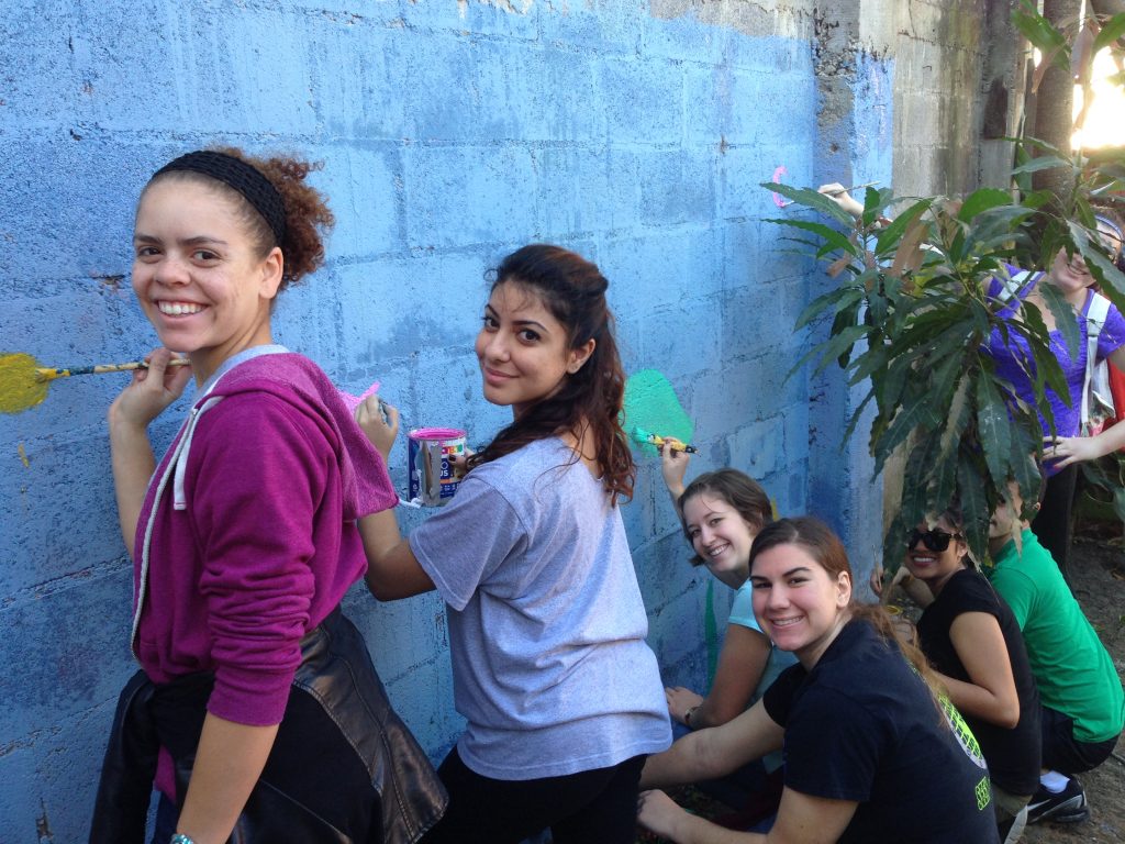 Adelphi students painting a wall abroad.