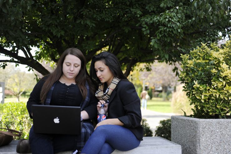 Two students using a laptop outside