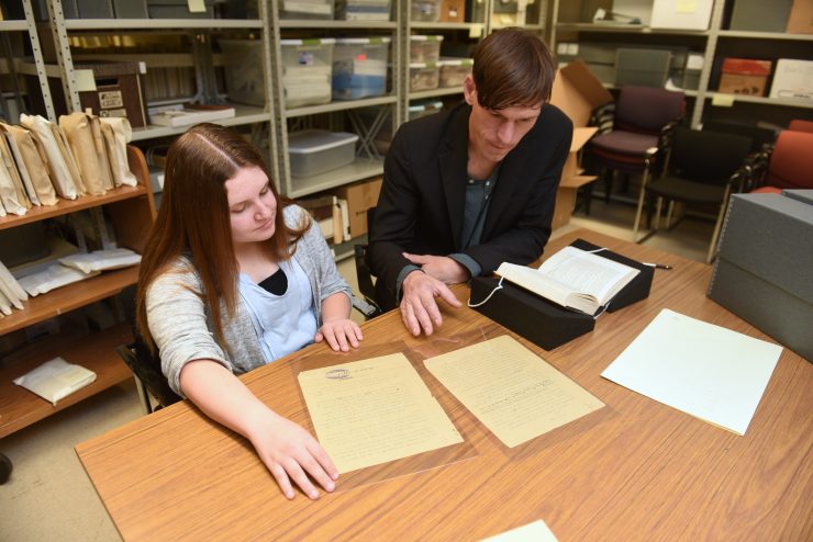 History major Nicole Quirke examines documents in Adelphi’s archives with Edward Reno, PhD, associate professor and chair of Adelphi’s history department.