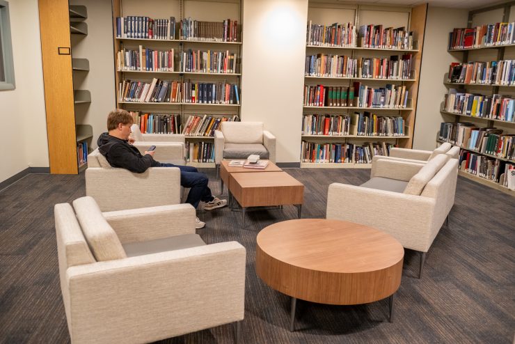 Swirbul Library First Floor. A student is studying in comfortable lounge chairs