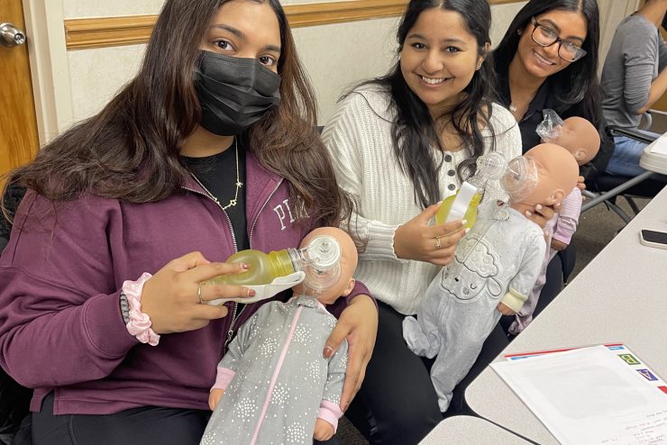 Students during a Adelphi University Student Nurses Association event holding simulation infants