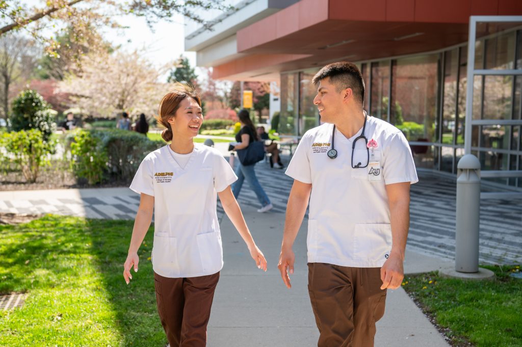 Adelphi students in the nursing program laugh together while walking in front of the Nexus Building on campus.