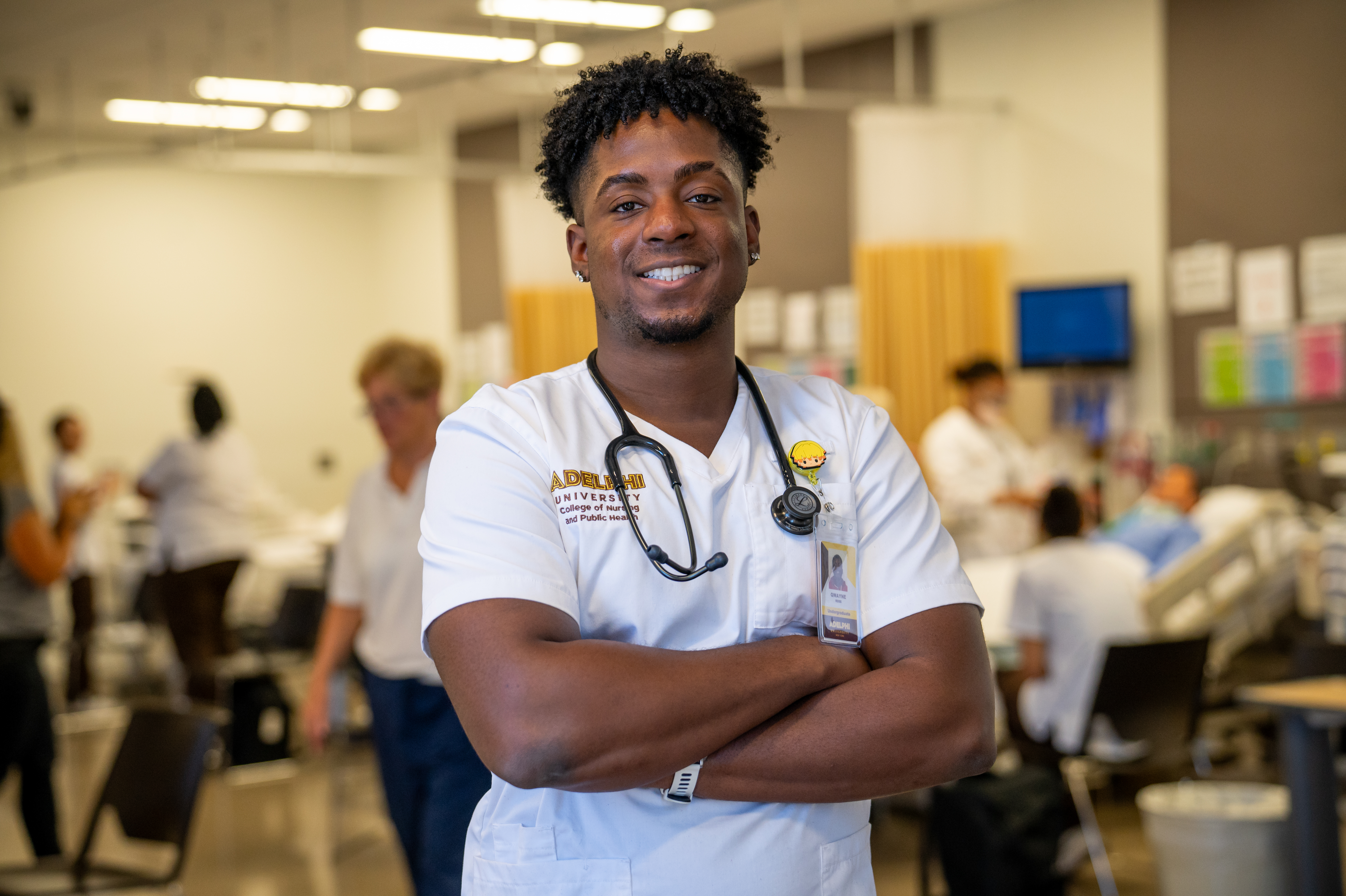 a proud male nursing student at Adelphi University standing in the state-of-the-art lab.