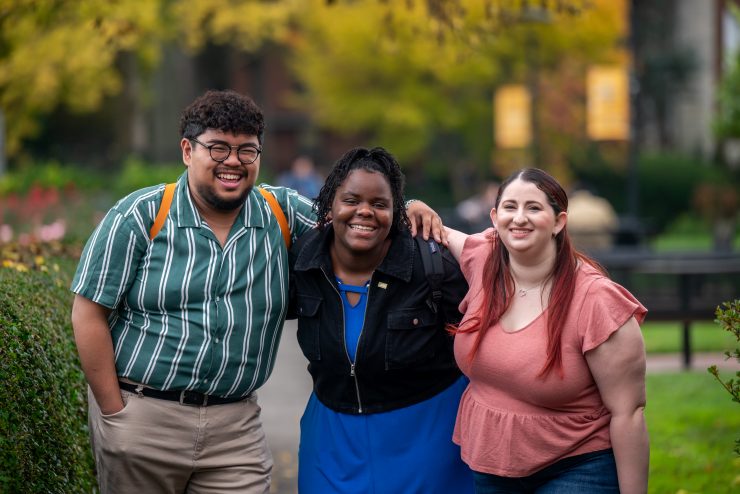 Three happy students laughing together on campus