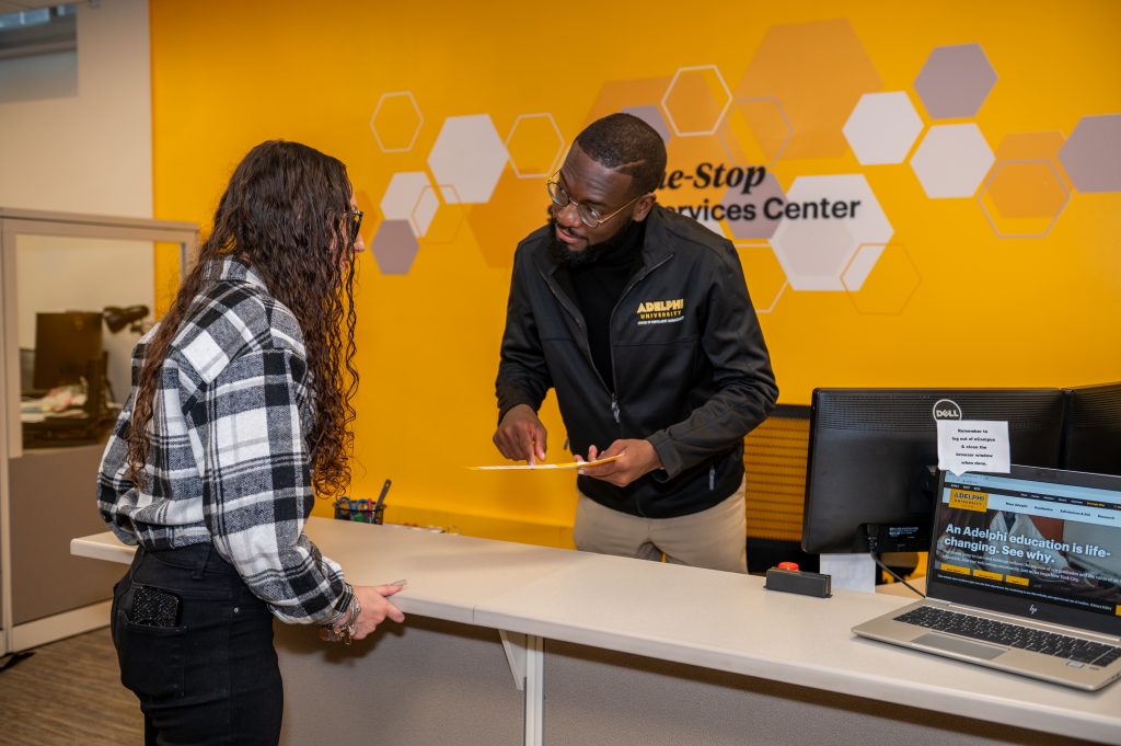 Adelphi aid counselor advising a student in front of the One Stop sign