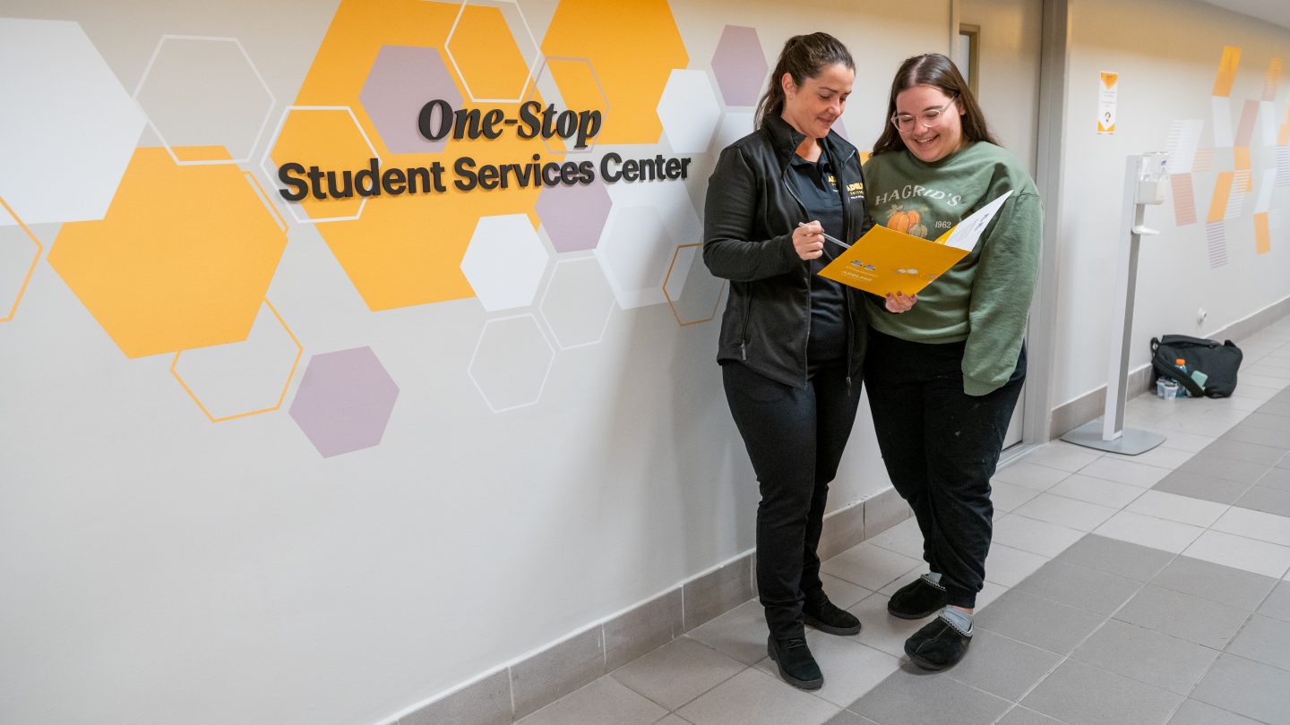 Adelphi financial aid counselor advising a student in front of the One Stop sign