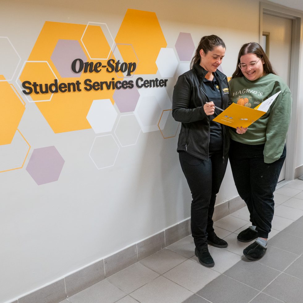 Adelphi financial aid counselor advising a student in front of the One Stop sign