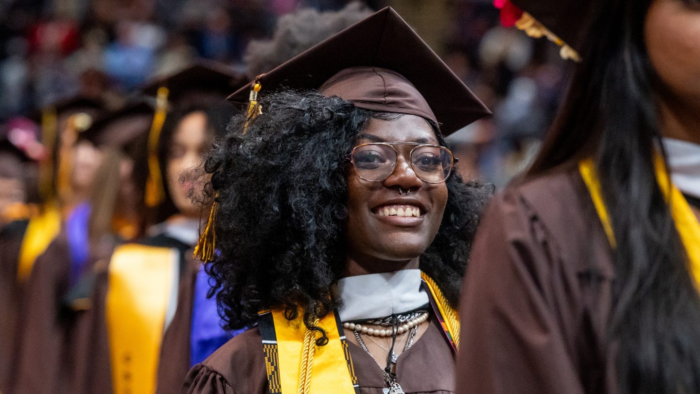 A joyful undergraduate in cap and gown at Adelphi University's commencement