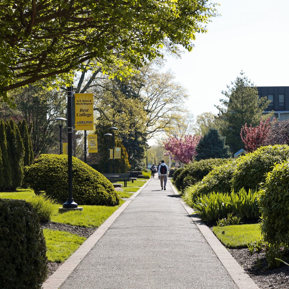 Adelphi lush green campus with students walking on the pathways.