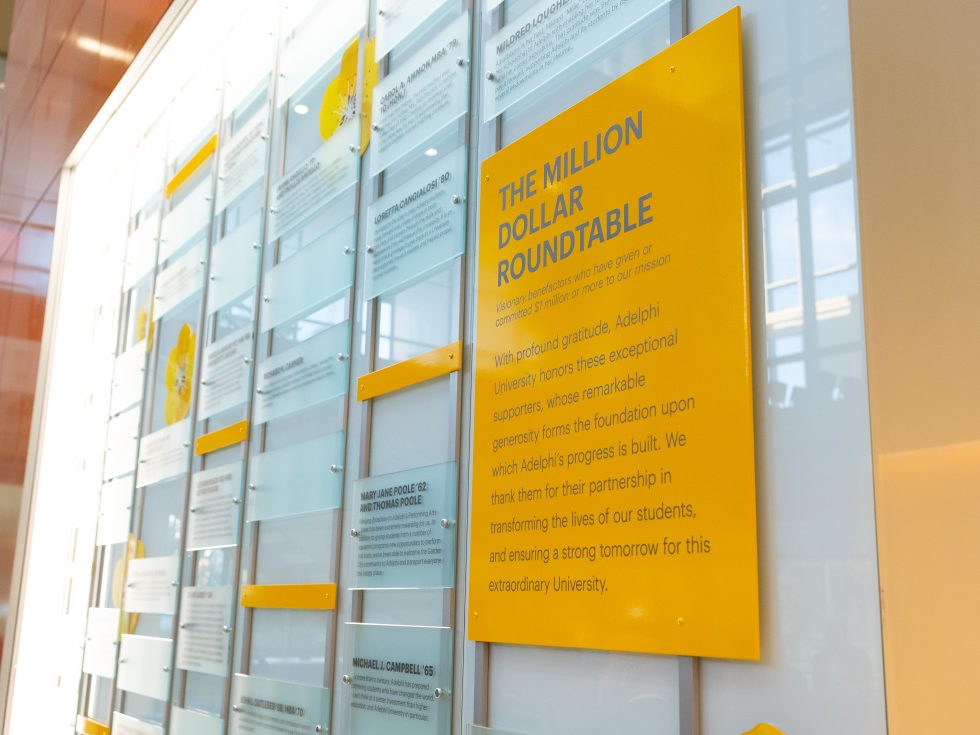 Adelphi Nexus Million Dollar Roundtable wall listing donor names.