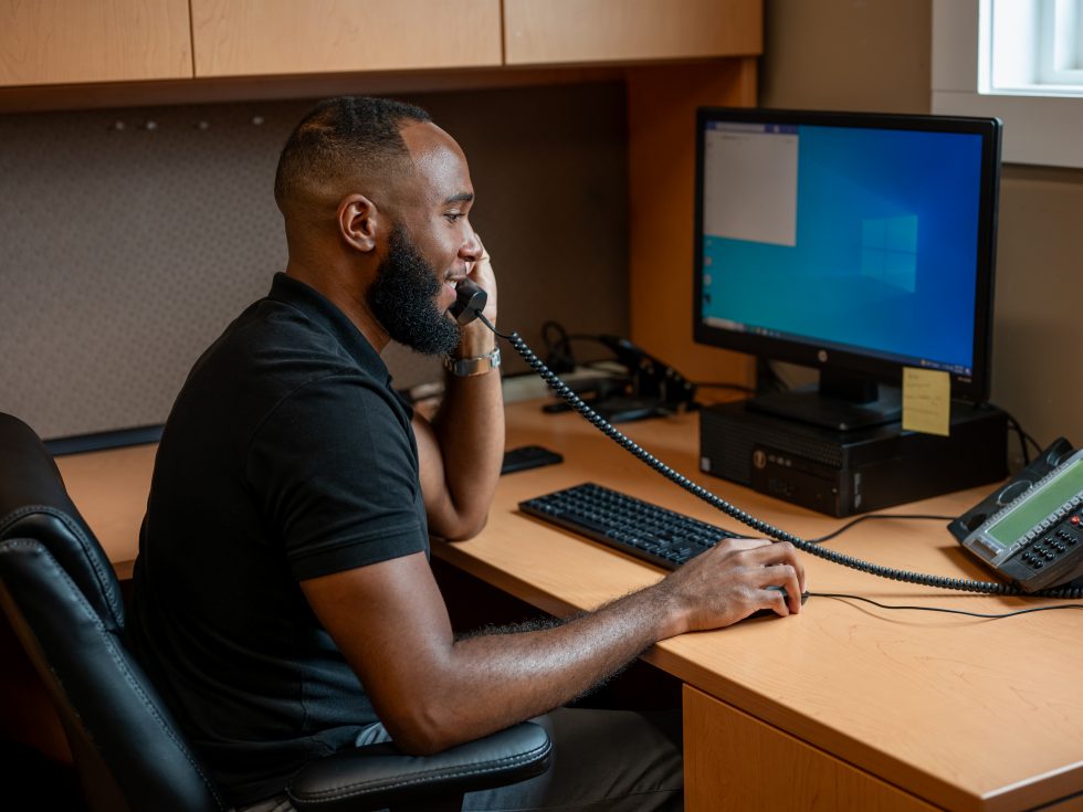 Man working at an office desk on the phone.