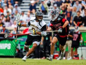 Lewis runs to his right cradling the ball as a University of Tampa player defends him.