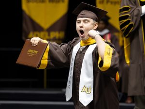 A male nursing students gives a shout onstage after receiving his diploma.