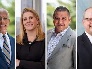 A collage of four professional head shot images, of 3 men and one woman, all wearing business attire.