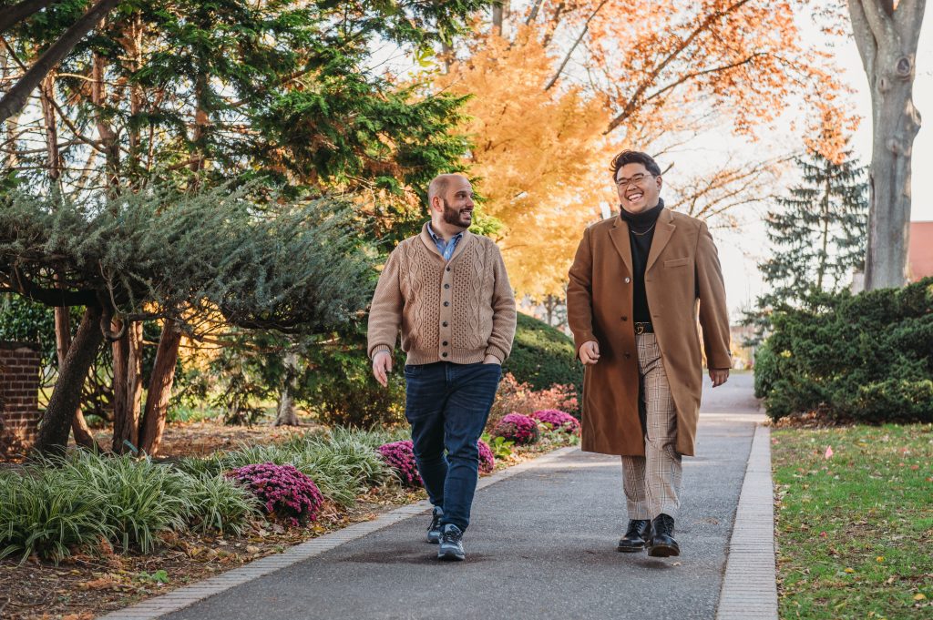 Two people walking on Adelphi University's beautiful autumn campus with the leaves changing.