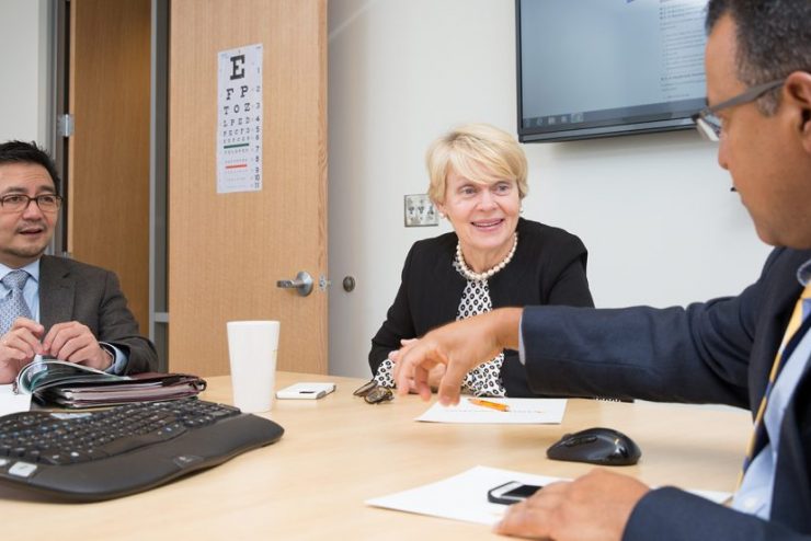 Three faculty members at a table having a discussion