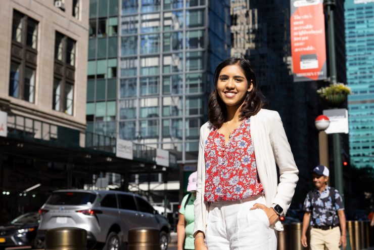 Student in the middle of New York City surrounded by buildings. 