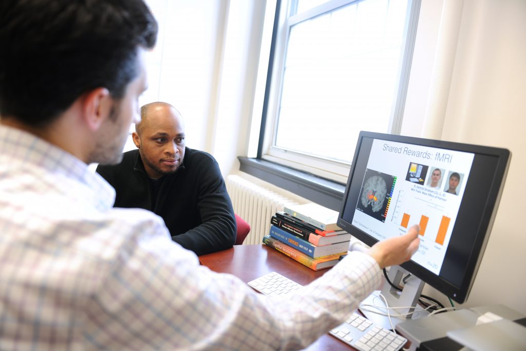 Students discuss neuroscience data at a computer screen.