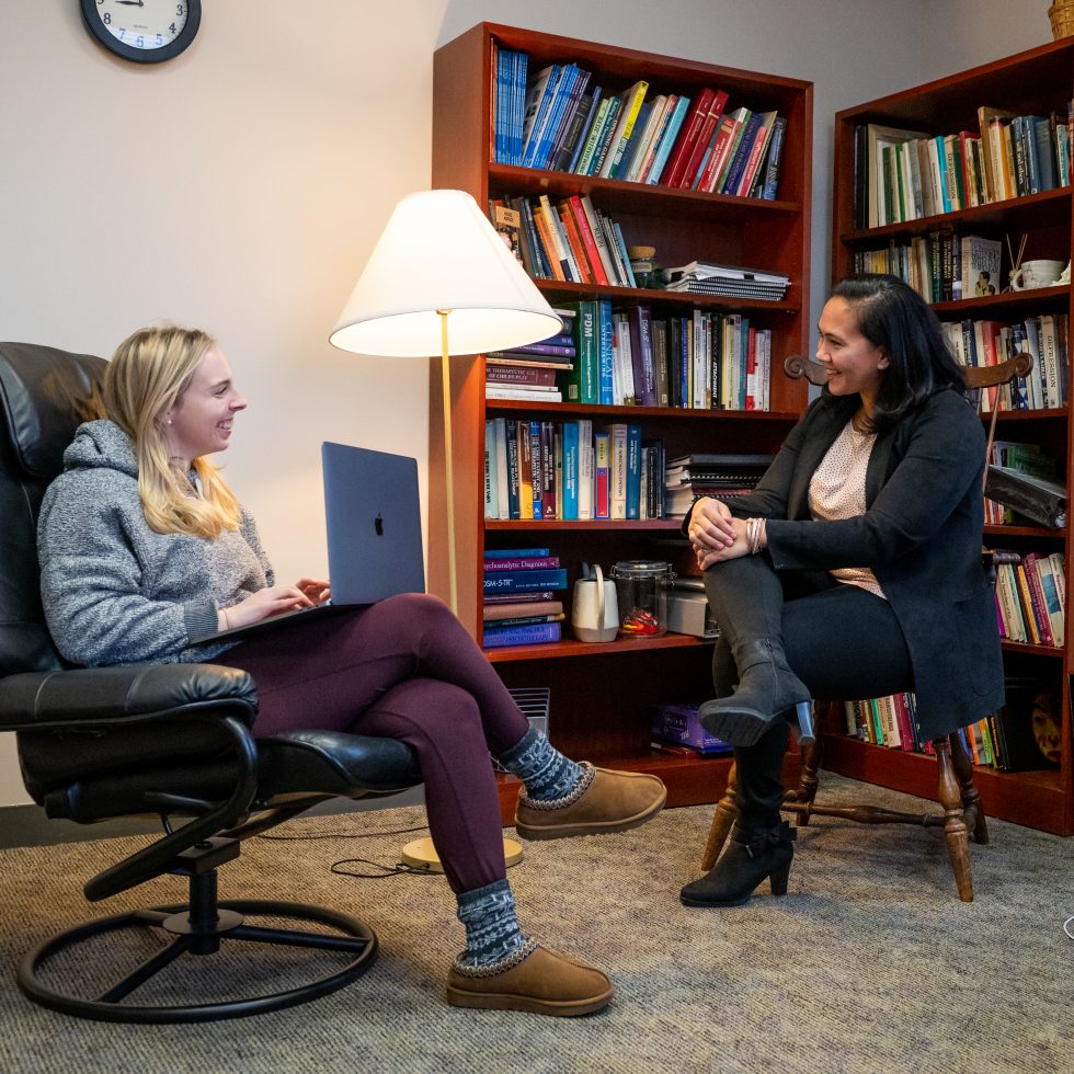 Monica Pal in an office with filled bookshelves mentoring a student.