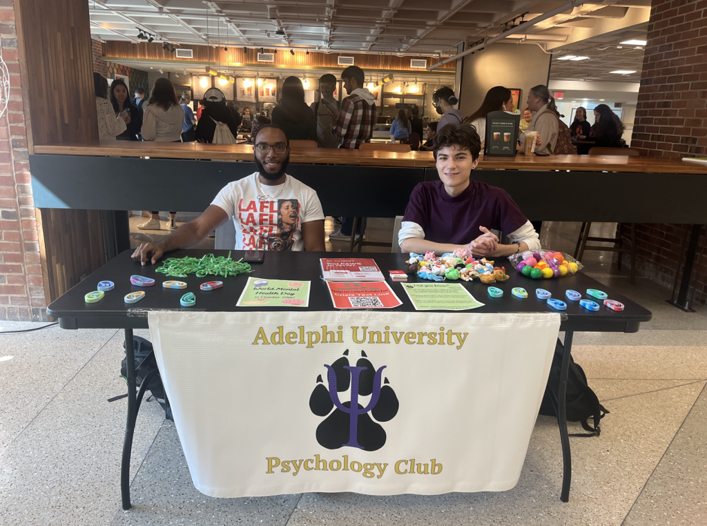 Adelphi Psychology Club - Members sitting at a table to bring awareness to campus.