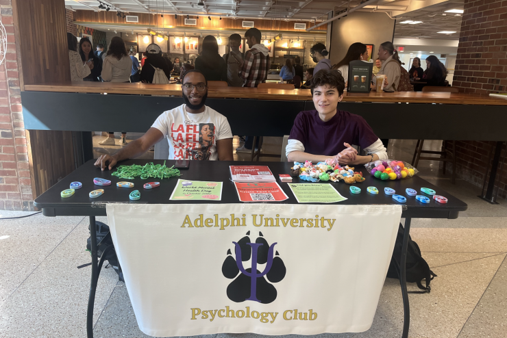 Adelphi Psychology Club - Members sitting at a table to bring awareness to campus.