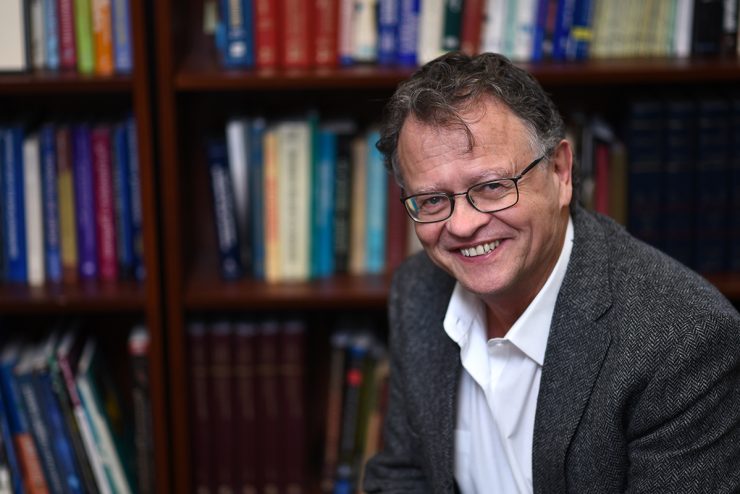 Jacques Barber, PhD seated in front of a bookshelf