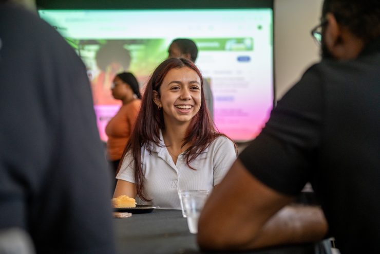 A Derner School student smiles with classmates during a mentoring session at Adelphi University