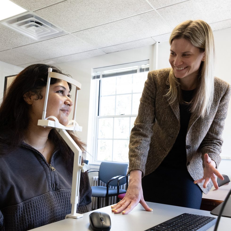 Professor Lempert with a neuroscience student explain a point in front of a computer with data showing on the screen.