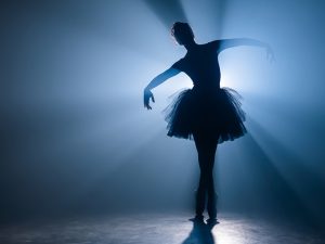 A solo ballet dancer's silhouette is outlined amid white and shades of blue.