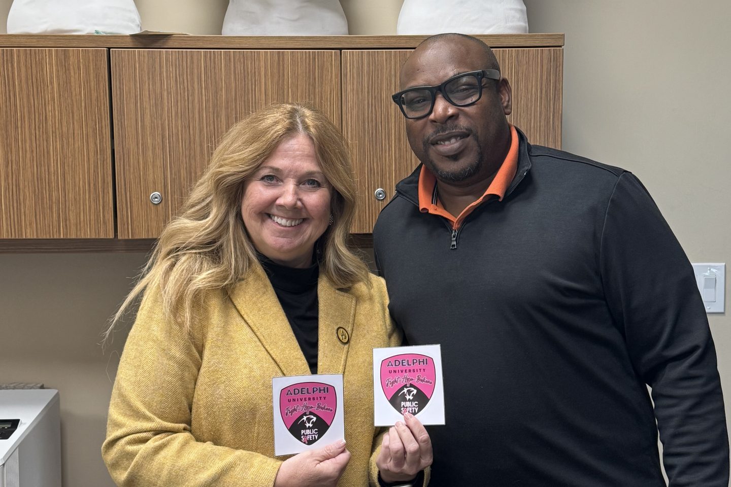 Carol Ann Boyle, Vice President of Campus Operations, and James Francies Assistant Vice President of Public Safety and Emergency Management holding their pink patches for Breast Cancer awareness.