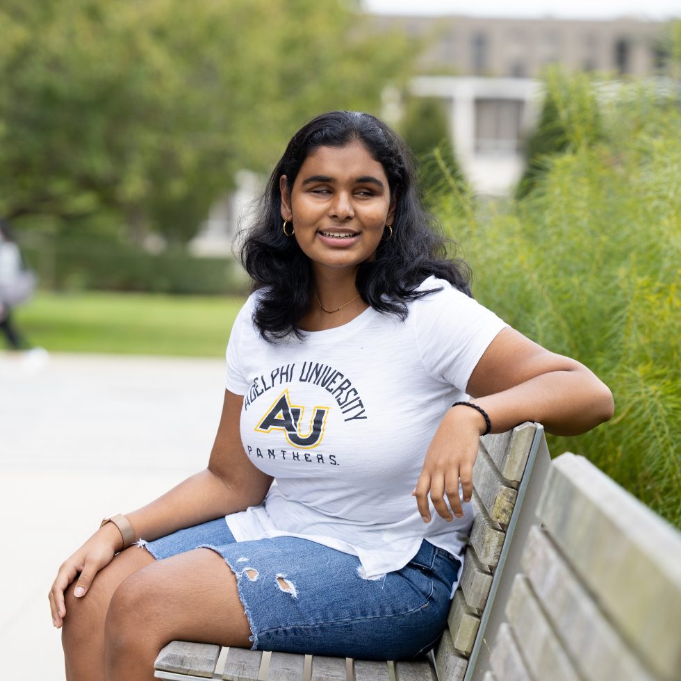 Jessica Karim sitting on a bench at Adelphi University's Garden City campus.